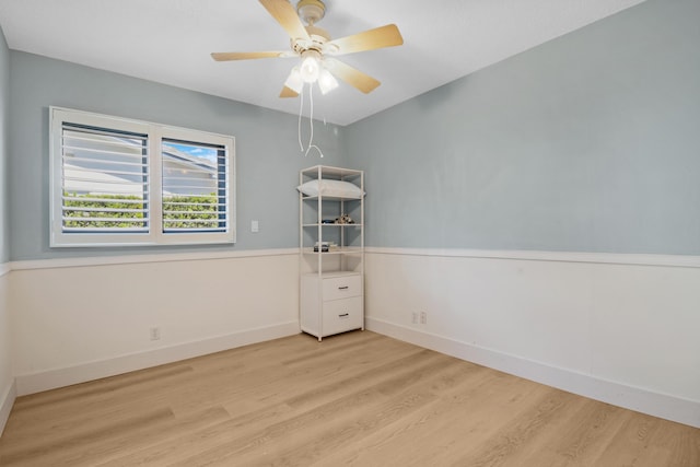 unfurnished room with wood finished floors, a ceiling fan, and baseboards