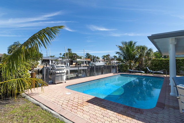 view of swimming pool featuring a water view, a patio area, fence, and a fenced in pool