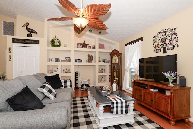 living room with lofted ceiling, ceiling fan, built in shelves, a textured ceiling, and wood-type flooring