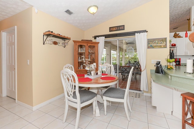 tiled dining area featuring a textured ceiling and vaulted ceiling