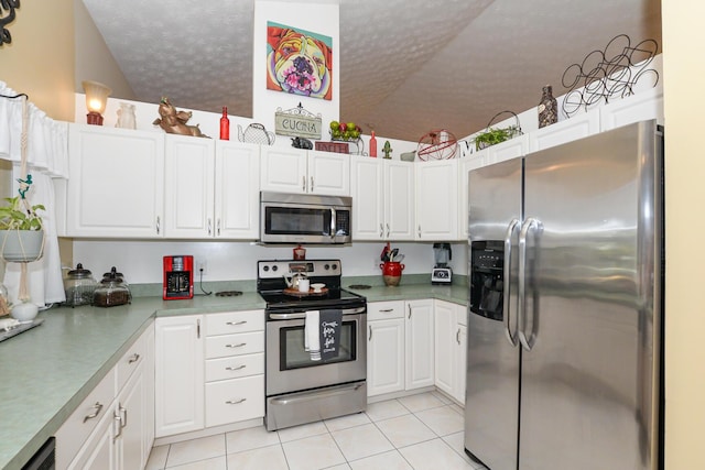 kitchen with white cabinetry, light tile patterned flooring, stainless steel appliances, and lofted ceiling