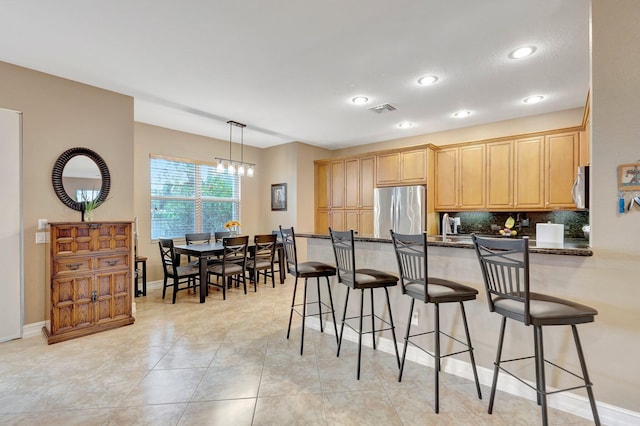 11606 Ponywalk Trl, Boynton Beach, FL 33473 - kitchen featuring stainless steel appliances, a peninsula, a kitchen bar, backsplash, and visible vents