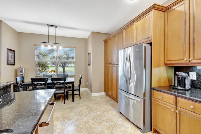 11606 Ponywalk Trl, Boynton Beach, FL 33473 - kitchen featuring hanging light fixtures, brown cabinets, light tile patterned floors, freestanding refrigerator, and dark stone countertops