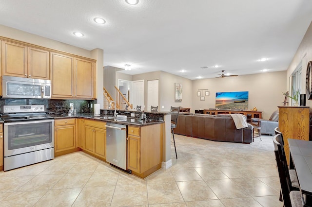 kitchen featuring stainless steel appliances, a kitchen bar, kitchen peninsula, and sink