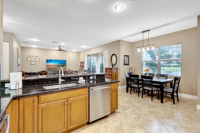 kitchen with decorative light fixtures, dishwasher, dark stone countertops, sink, and plenty of natural light