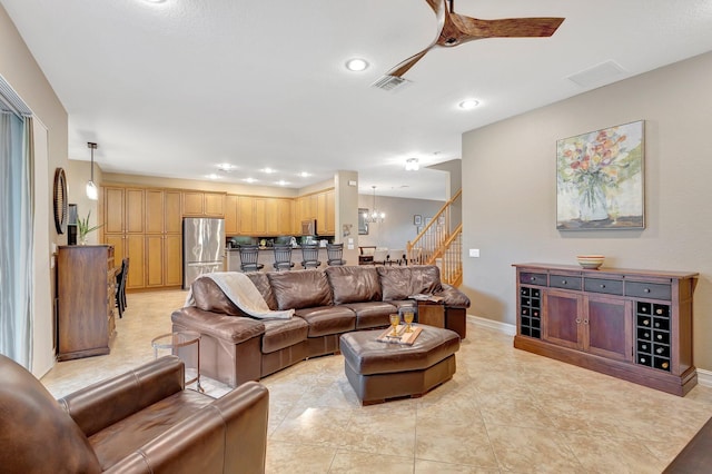 tiled living room with ceiling fan with notable chandelier