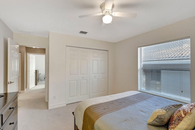 bedroom with ceiling fan, a closet, and light carpet