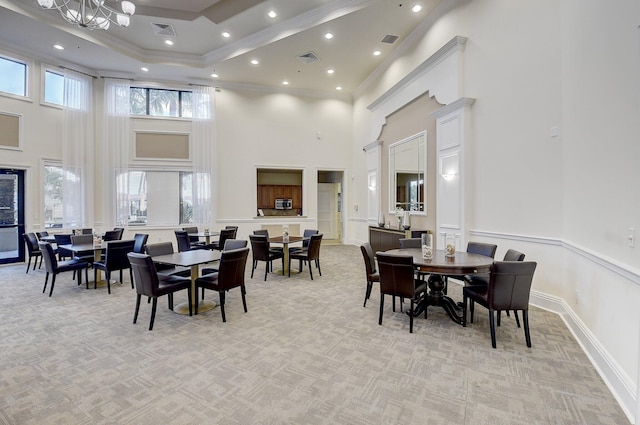 carpeted dining area with a raised ceiling, crown molding, and a towering ceiling