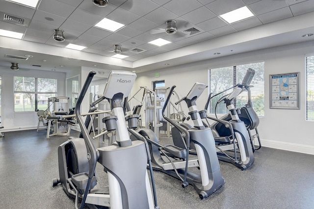 workout area featuring ceiling fan, a drop ceiling, and a wealth of natural light