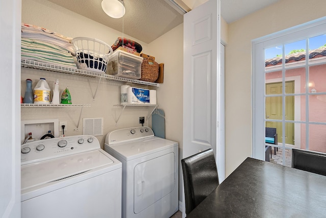 laundry area with washing machine and clothes dryer and a textured ceiling