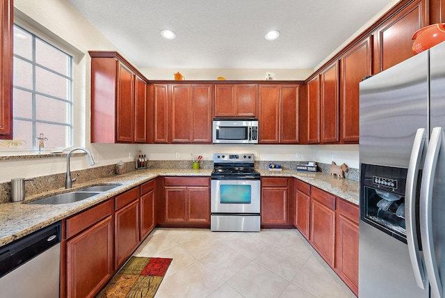 kitchen featuring light tile patterned floors, appliances with stainless steel finishes, sink, and light stone counters