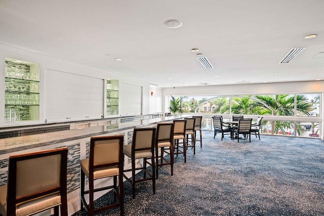 kitchen featuring white cabinets, a breakfast bar, and dark carpet