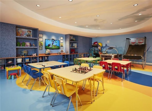 game room with built in shelves and a tray ceiling