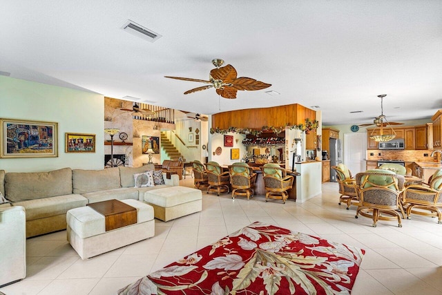 living room with ceiling fan, a textured ceiling, light tile patterned floors, and a fireplace