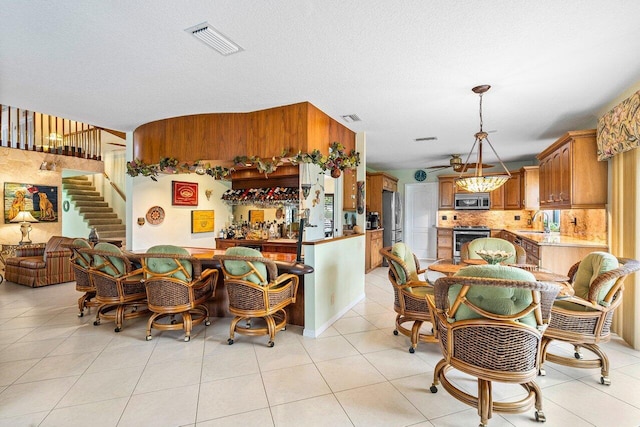 tiled dining space featuring wet bar and a textured ceiling