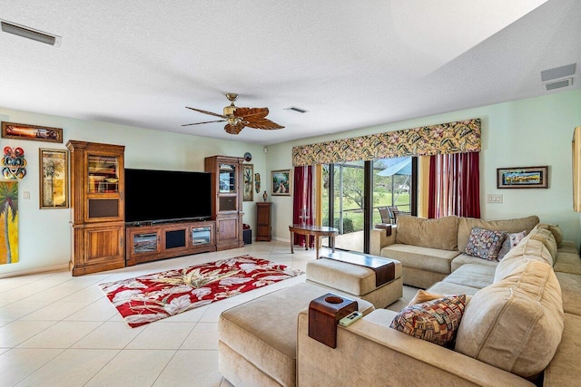 living room with ceiling fan, light tile patterned floors, and a textured ceiling