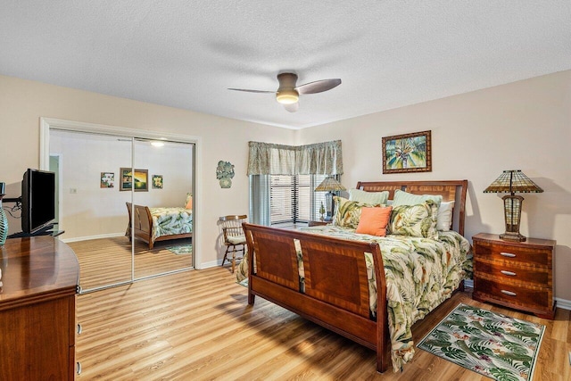 bedroom with ceiling fan, a closet, a textured ceiling, and light hardwood / wood-style flooring