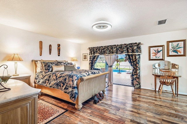 bedroom featuring access to exterior, dark hardwood / wood-style flooring, and a textured ceiling