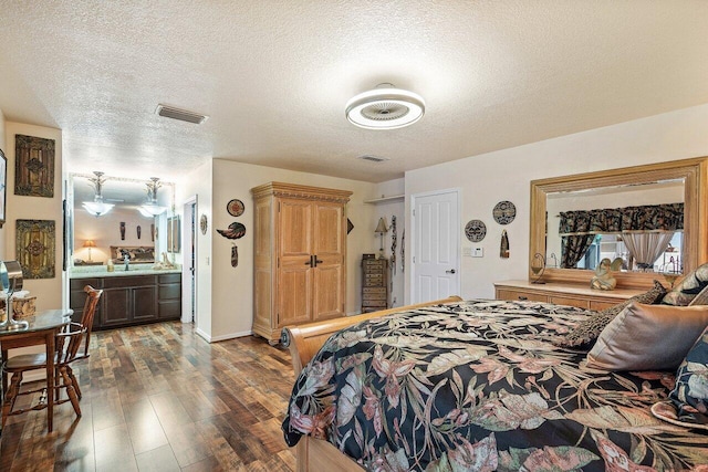 bedroom featuring a textured ceiling, dark wood-type flooring, connected bathroom, and sink