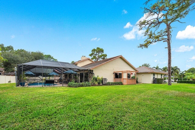 back of property with a lanai, a yard, and central AC unit