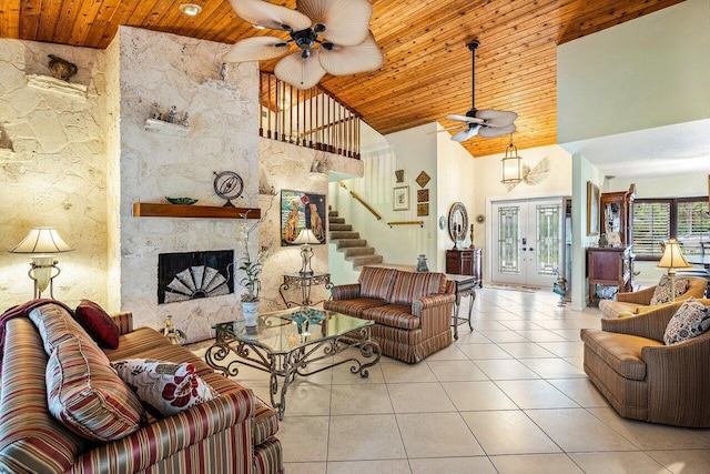 living room featuring high vaulted ceiling, light tile patterned floors, french doors, and a stone fireplace