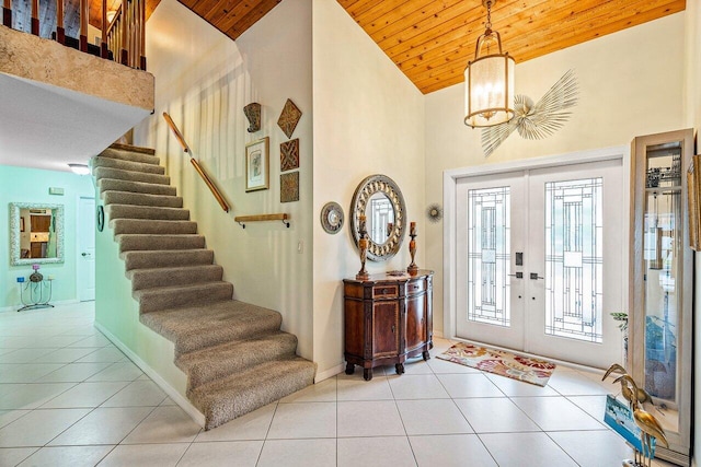 tiled entryway with high vaulted ceiling, wooden ceiling, french doors, and an inviting chandelier