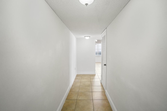 corridor featuring light tile patterned floors and a textured ceiling