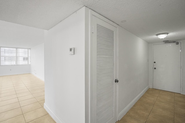 hall with a textured ceiling and light tile patterned flooring