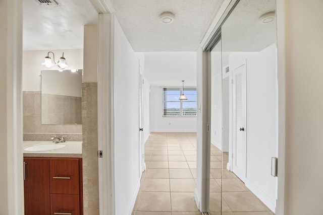 bathroom featuring tile patterned floors, vanity, a textured ceiling, and an inviting chandelier