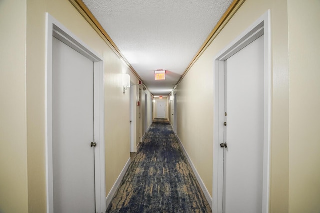 hallway with a textured ceiling and crown molding