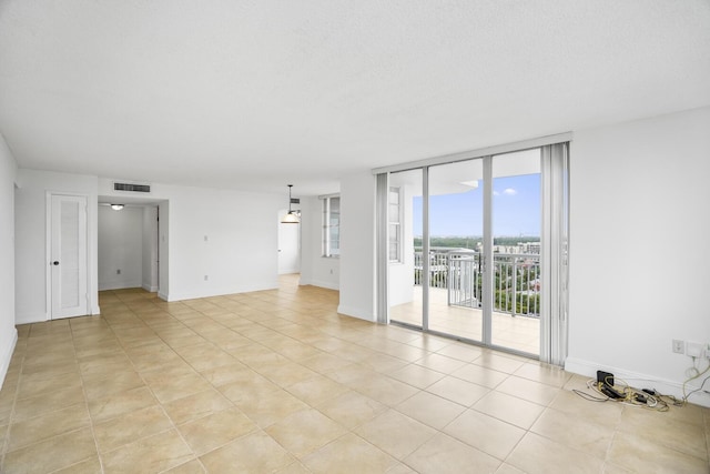 spare room featuring a textured ceiling, a wall of windows, and light tile patterned flooring