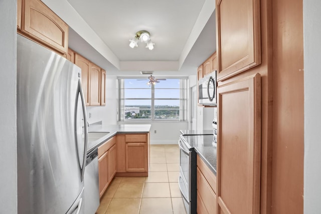 kitchen with light tile patterned floors, stainless steel appliances, a raised ceiling, and light brown cabinetry