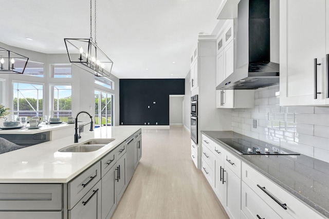 kitchen featuring sink, white cabinetry, wall chimney exhaust hood, and a kitchen island with sink