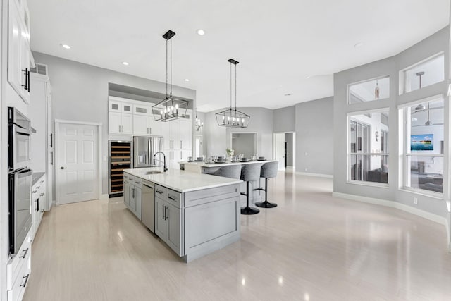 kitchen featuring pendant lighting, a center island with sink, sink, white cabinetry, and appliances with stainless steel finishes