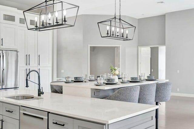 kitchen featuring a kitchen island with sink, white cabinets, hanging light fixtures, light hardwood / wood-style flooring, and sink