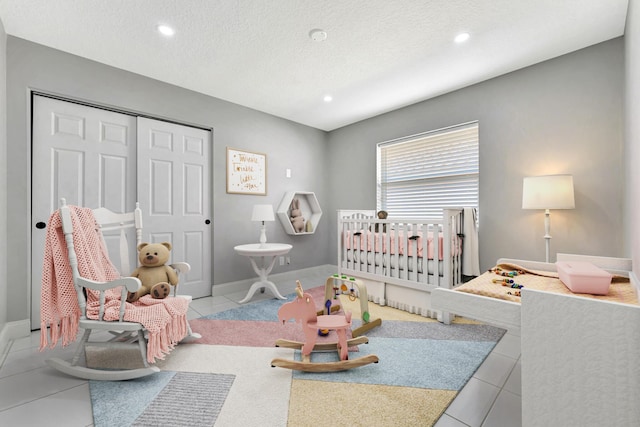 tiled bedroom with a textured ceiling, a closet, and a crib