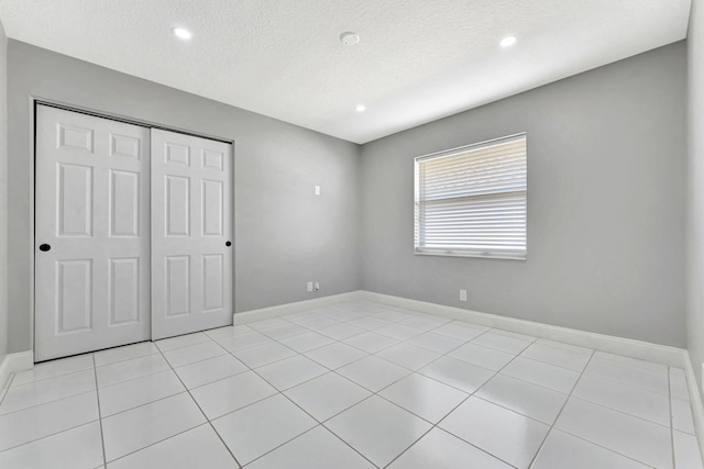 unfurnished bedroom with a textured ceiling, a closet, and light tile patterned flooring