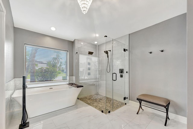 bathroom with a notable chandelier and shower with separate bathtub