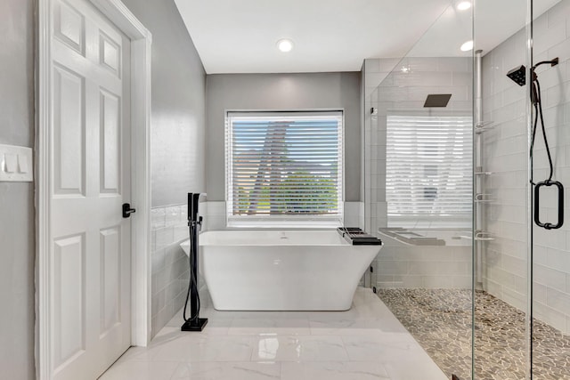 bathroom with tile walls and independent shower and bath