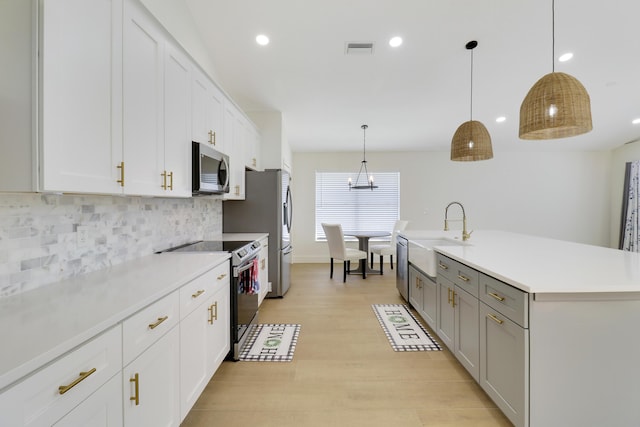 kitchen with white cabinetry, sink, pendant lighting, and stainless steel appliances