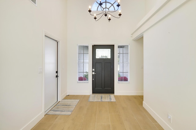 foyer featuring a high ceiling, a chandelier, and light wood-type flooring