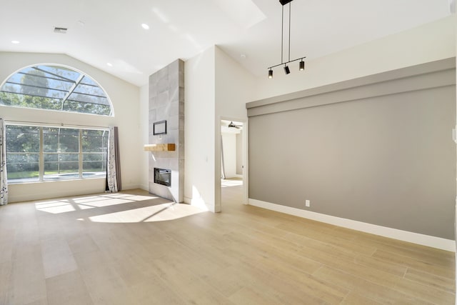 unfurnished living room featuring light hardwood / wood-style floors, high vaulted ceiling, ceiling fan, and a fireplace