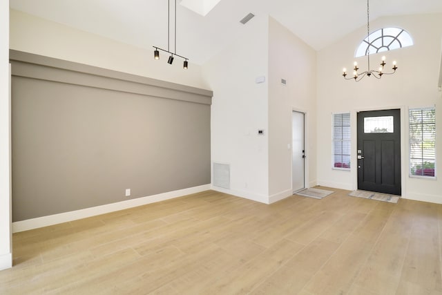 foyer with high vaulted ceiling, wood-type flooring, and a chandelier