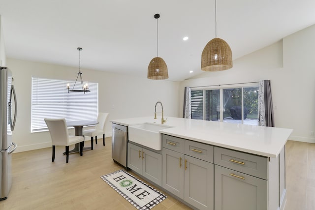 kitchen with a center island with sink, sink, hanging light fixtures, appliances with stainless steel finishes, and gray cabinetry