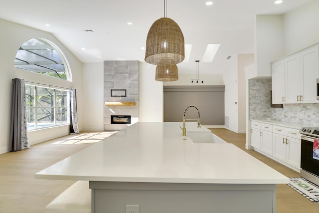 kitchen featuring stainless steel electric range oven, sink, pendant lighting, and a large island