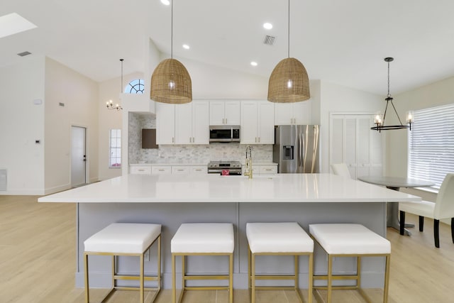 kitchen with a spacious island, appliances with stainless steel finishes, tasteful backsplash, hanging light fixtures, and a notable chandelier