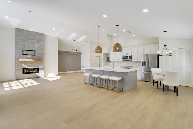 kitchen featuring a spacious island, pendant lighting, appliances with stainless steel finishes, white cabinetry, and decorative backsplash