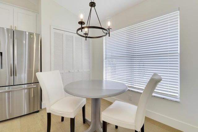 dining area with light wood-type flooring, a chandelier, and lofted ceiling