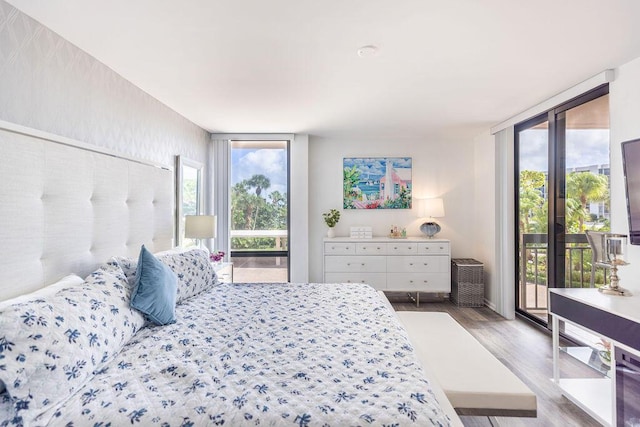 bedroom featuring expansive windows, wood-type flooring, and access to outside