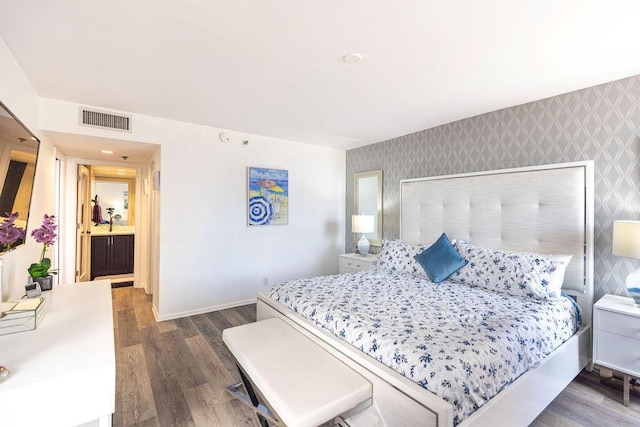 bedroom featuring connected bathroom and dark hardwood / wood-style flooring